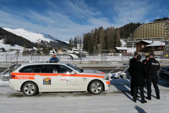 Schweizer Polizisten stehen neben einem Polizeiauto